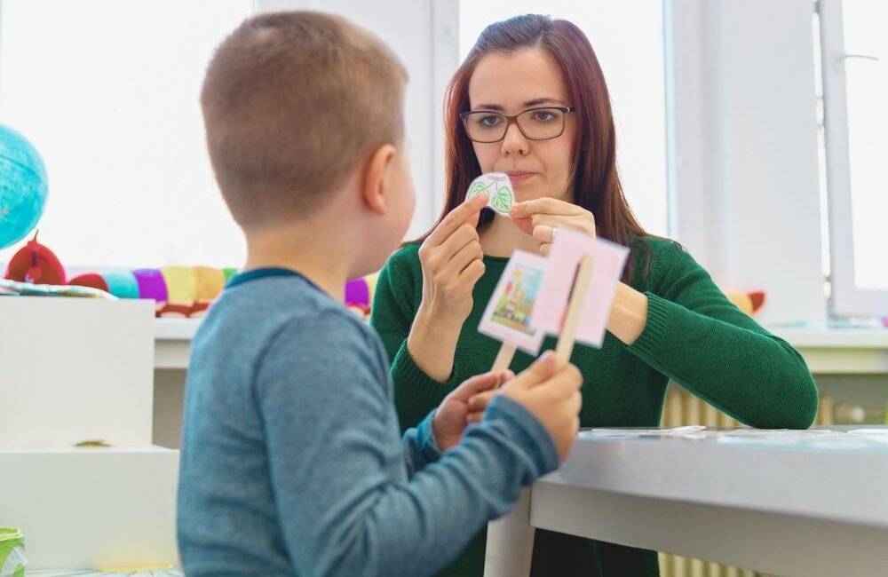 Fonoaudióloga infantil ajudando uma criança a desenvolver habilidades de comunicação social.