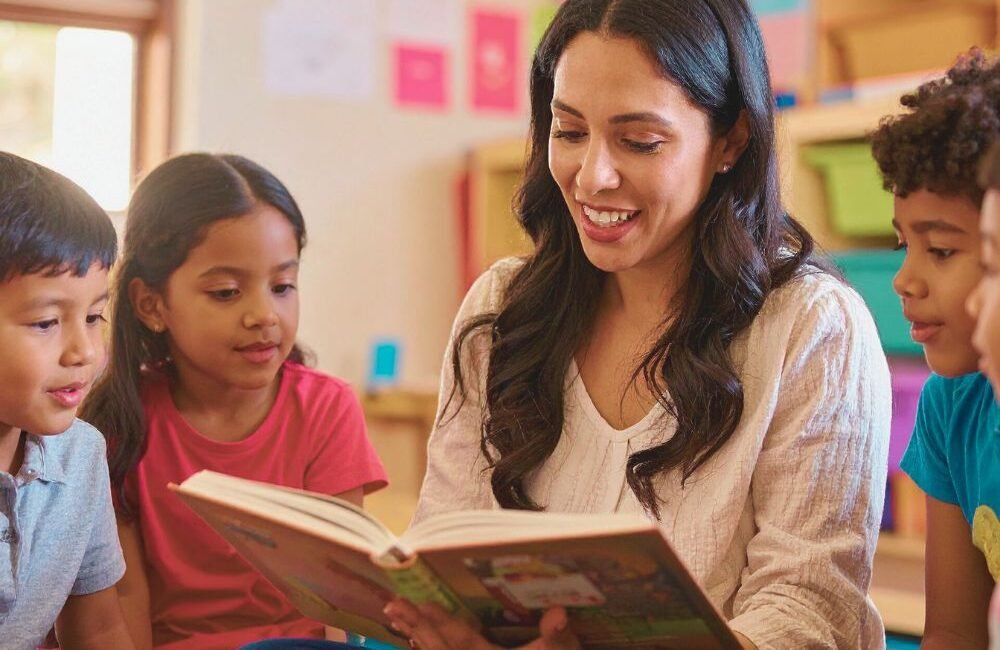 Crianças em atividade de leitura com apoio da professora.