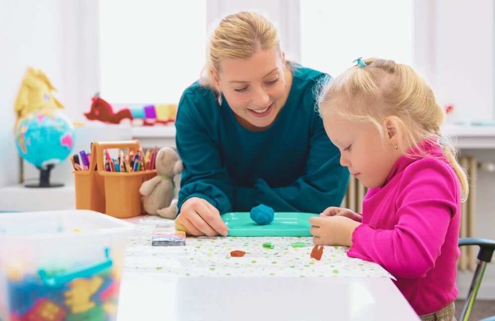 Fonoaudióloga ensinando criança durante avaliação fonoaudiológica infantil