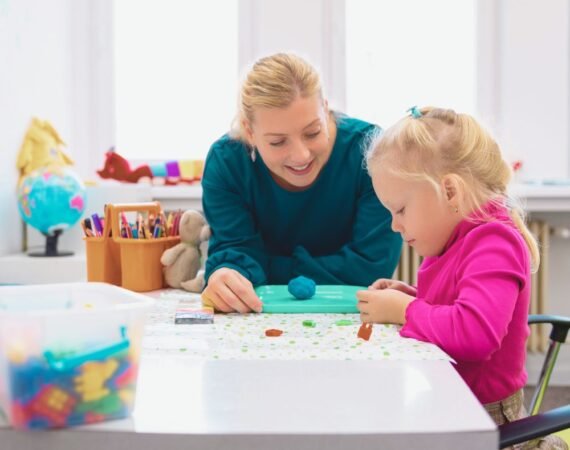 Fonoaudióloga ensinando criança durante avaliação fonoaudiológica infantil