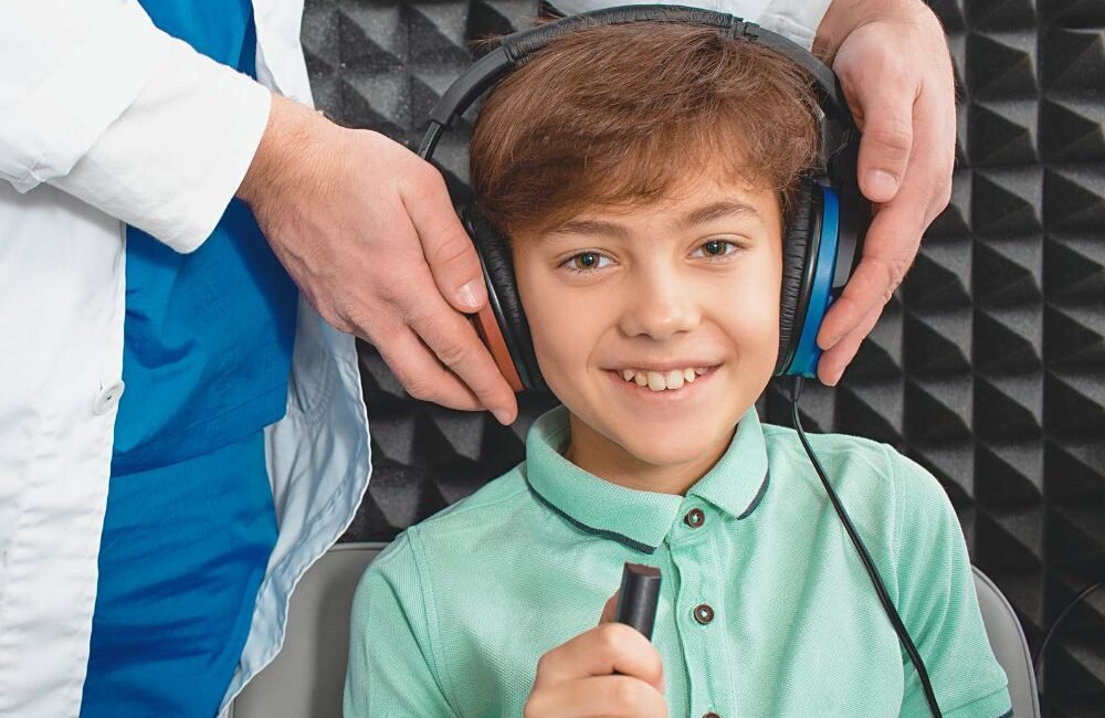 Criança em sessão de terapia fonoaudiológica dentro de cabine acústica