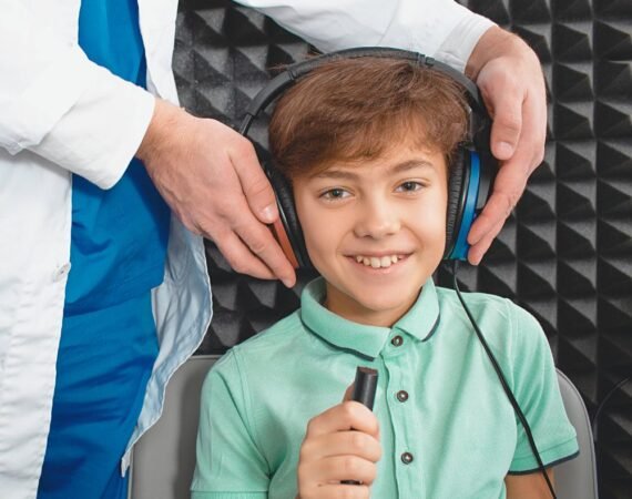 Criança em sessão de terapia fonoaudiológica dentro de cabine acústica