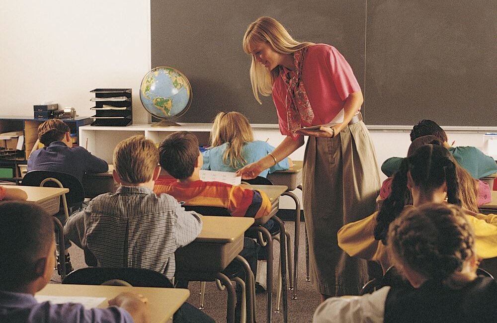 Criança em sala de aula acompanhando explicação durante atividade escolar.