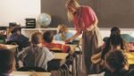Criança em sala de aula acompanhando explicação durante atividade escolar.