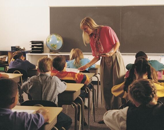 Criança em sala de aula acompanhando explicação durante atividade escolar.