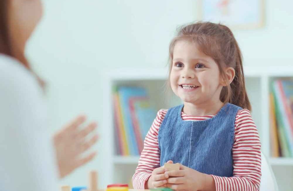Fonoaudióloga infantil acompanhando criança durante uma atividade de linguagem.