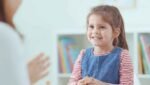 Fonoaudióloga infantil acompanhando criança durante uma atividade de linguagem.